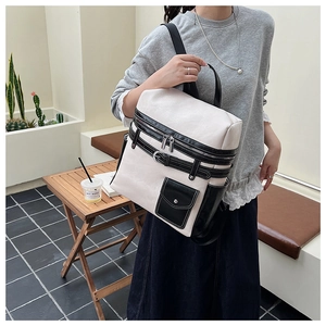 Fashionable beige and black contrasting leather backpack worn by a model in outdoor setting