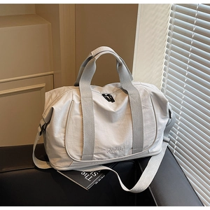Détail du sac de voyage en nylon gris clair imperméable sur canapé cuir avec bandoulière