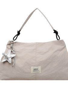 Beige pleated nylon tote bag with black knot detail and star charm on white background