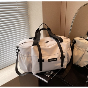 Détail du sac de voyage gris clair avec sangles noires et poches latérales à cordon