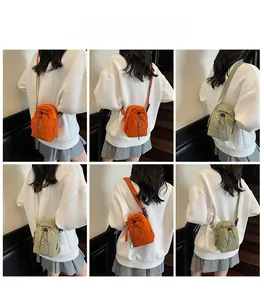 Detail of mini drawstring nylon crossbody bag in bright orange and light green colors