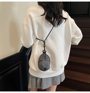 Detailed view of mini baseball cap crossbody bag in dark grey with woven strap