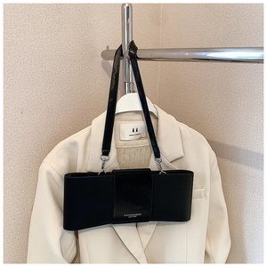Detail of black bow shoulder bag with leather patchwork and metal strap hardware