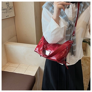 Detail of red patent leather tote bag with silver hardware and adjustable wide shoulder strap