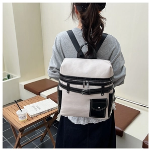 Detail of a two-tone PU leather backpack featuring dual zippers and a magnetic front pocket