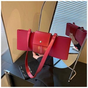 Detail of red bow-shaped leather handbag with silver metallic buckle and shoulder strap