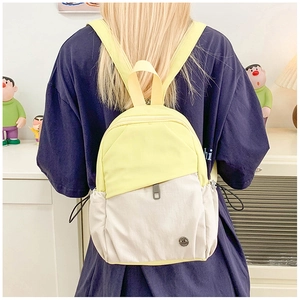 Mini sac à dos multi-poches en nylon jaune et beige porté par un mannequin en extérieur