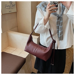 Detail of burgundy leather hobo bag with decorative knot and long tassel fringe