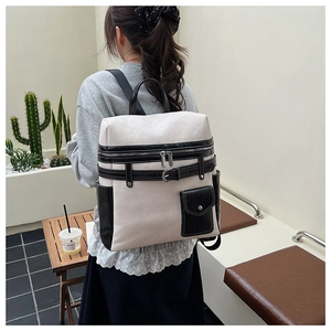 Detail view of the multi-zipper compartments and decorative buckle on the stylish backpack