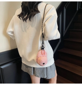 Pink baseball cap shaped mini crossbody bag worn by model on a stylish strap