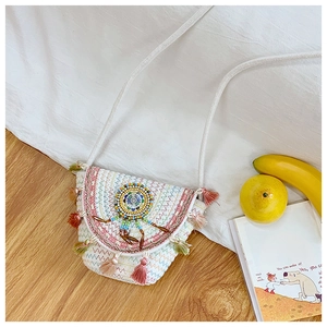 Detail of woven straw bucket bag with colorful tassel fringe and beaded mandala pattern