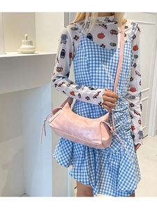 Borsa a tracolla rosa a forma di mezzaluna con nappe indossata da modella su fondo bianco