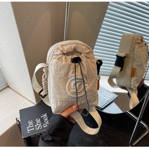 Detail of cream-white nylon crossbody bag with drawstring closure and texture detail