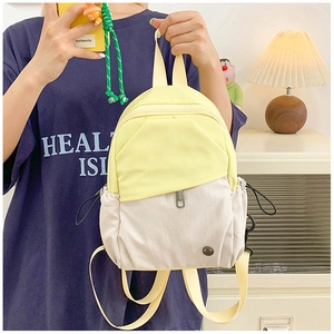 Detail of a mini waterproof nylon backpack in yellow and beige with front metal logo