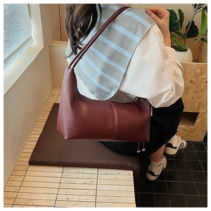 Detail of burgundy leather hobo bag with contrast stitching and metal ball charm
