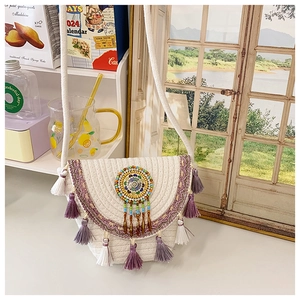 Detail of woven straw bucket bag featuring purple tassels and colorful beadwork ornament