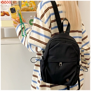 Mini black nylon backpack on a model showing compact size and stylish casual design