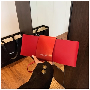 Detailed view of red bow-shaped crossbody bag with FASHION & BAGS white lettering