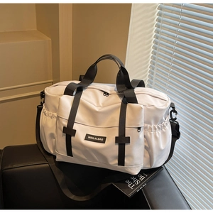 Détail d'un grand sac de voyage blanc avec des sangles noires et bandoulière amovible