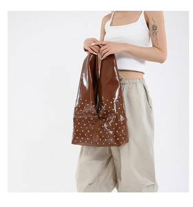 Détail du sac cabas en cuir brillant marron foncé avec rivets argentés et forme style hobo