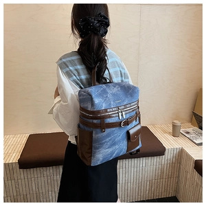 Close-up of vintage blue canvas backpack with brown leather trim and metal zippers