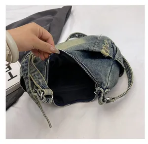 Detail view of denim shoulder bag featuring secure zip closure and internal zip pocket
