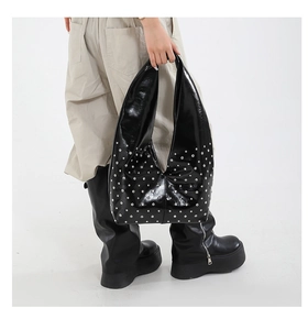 Détails du sac hobo en cuir verni noir avec clous punk argentés et finition brillante