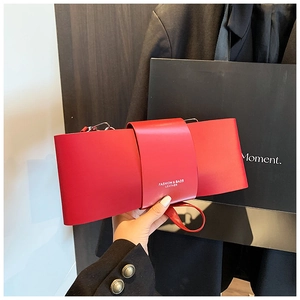 Close-up of a red leather bow bag featuring metal hardware and gold logo printing