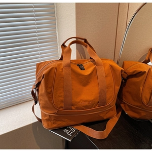 Vue détaillée du grand sac de voyage orange caramel avec texture et broderie fine
