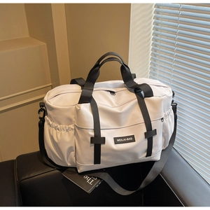 Détail du grand sac de voyage blanc avec poche avant et logo WEILAI-BAG sur canapé noir