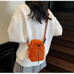 Detail of bright orange nylon crossbody phone bag with drawstring and zipper pocket