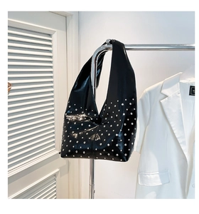 Détail du sac hobo noir orné de rivets argentés présenté sur un support métallique