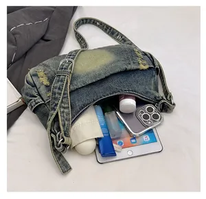 Spacious interior of denim crossbody bag showing storage for tablet and cosmetics