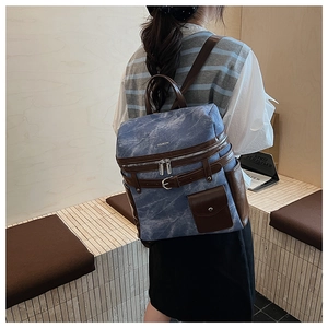 Detail of blue textured backpack with brown leather straps and vintage buckle design