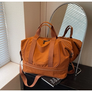 Détail d'un grand sac de voyage orange en nylon imperméable avec une large bandoulière