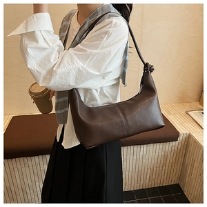 Detail of a dark brown crescent underarm bag with decorative stitching and shoulder knot