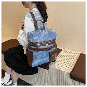 Detail of blue canvas backpack with brown leather straps and front pocket for hiking