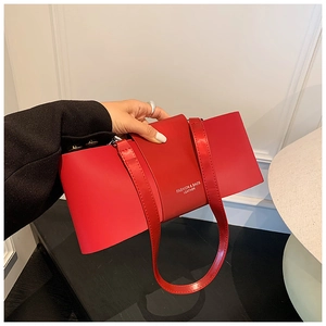 Close-up of a red leather shoulder bag featuring a unique bow-shaped minimalist design