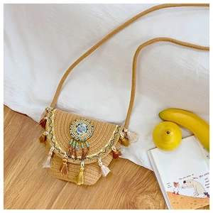 Detailed shot of ethnic straw bucket bag with colorful bead patterns and vibrant tassels