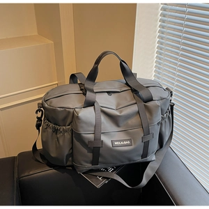 Détail du sac de fitness en nylon gris avec poignées renforcées sur un canapé noir