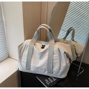 Détail du sac de voyage gris avec larges poignées en nylon durable pour le sport