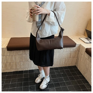 Detail of dark brown leather hobo bag featuring a unique knot decorative shoulder strap