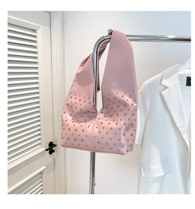 Vue détaillée du sac rose brillant avec rivets argentés sur un cintre métallique