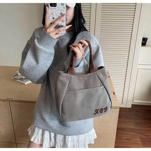 Detail of grey canvas tote bag with XQY letter embroidery and brown woven handles