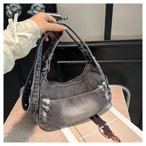 Detail view of distressed grey denim shoulder bag with metal eyelets and zipper closure