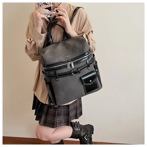 Detail of a charcoal grey and black backpack featuring multiple pockets and metal buckles