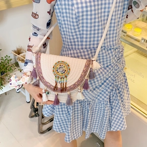 Detailed shot of white woven straw bucket bag with colorful beads and tassel trim