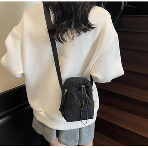 Detail of lightweight black drawstring crossbody bag showing embroidery and strap detail