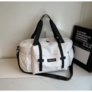 Vue détaillée du grand sac de voyage blanc avec sangles noires sur marbre