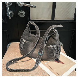 Detail of distressed denim hobo bag with silver eyelets and adjustable wide shoulder strap